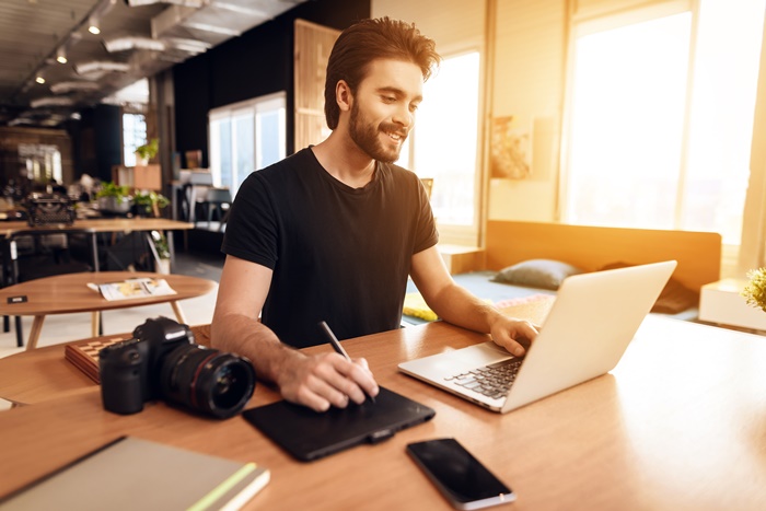 Junger Mann beim Bearbeiten von Fotos am Laptop