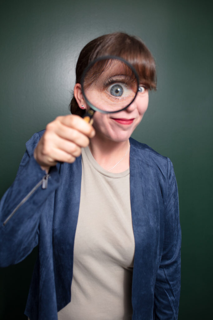 Nina Kirsch schaut durch Lupe in die Kamera