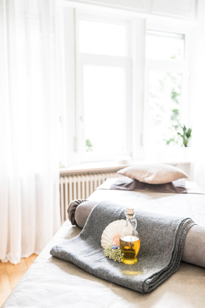 Foto eines hellen Raumes mit einer Massageliege.