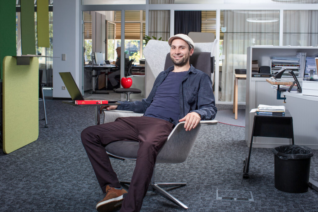 Malchus Kern sitzt lässig auf einem Stuhl im Büro.