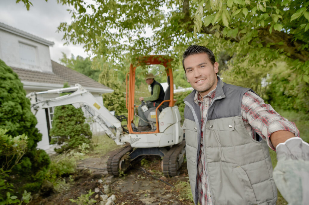 Bild von zwei Gartenbauern bei der Arbeit. Einer ist im Bagger.