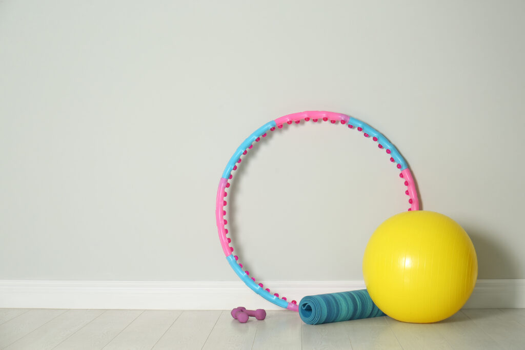Bild von einem Hula Hoop Reifen, Yogamatte, Handeln und einem Gymnastikball.